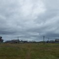 Вертолет улетает и в голове что-то переключается. Всё, назад уже пути нет. Мы в селе без связи где-то в горле Белого моря, и выбраться отсюда можно только через неделю тем же рейсом.Подумать только, прошло уже 3 дня с отправления из Москвы, а мы даже не начали грести, никогда еще подход под маршрут не занимал у нас столько времени.Замечаем три современных ветряка: один стоит, но неподвижен и два на земле. Оказывается, их поставили недавно, но кто-то видать где-то распилил и накосячил с обслуживанием, так что вместо энергии ветра вся деревня использует дизельный генератор, включающийся на несколько часов в день. Вот такая альтернативная энергетика.Под начавшимся дождем таскаем вещи к побережью, ставим палатку, готовим обед в нашем “ангаре”. С первого раза палатка оправдывает себя на все 100. В ней много места, удобно сидеть, удобно готовить в дождь.